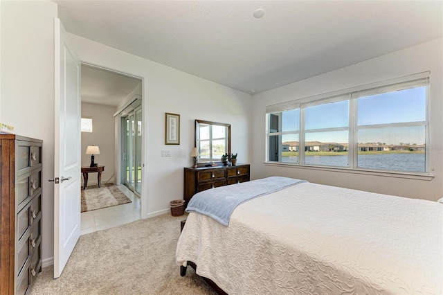 bedroom with a water view and light colored carpet