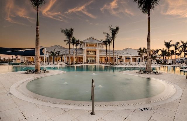 pool at dusk featuring pool water feature