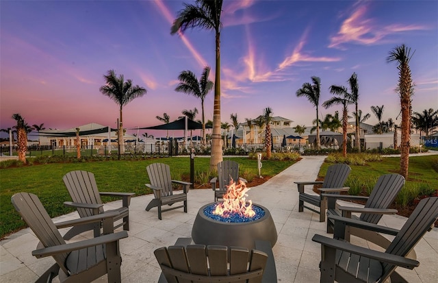 patio terrace at dusk featuring a yard and an outdoor fire pit