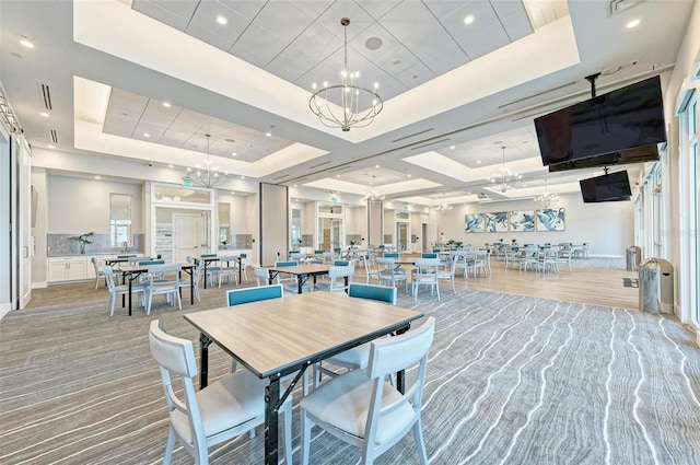 dining room with a tray ceiling, carpet, and a chandelier