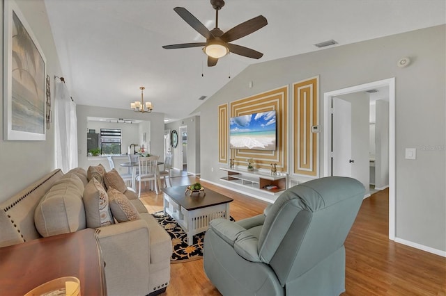 living room with lofted ceiling, light hardwood / wood-style flooring, and ceiling fan with notable chandelier