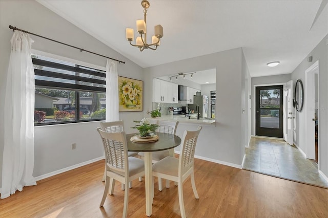 dining space featuring lofted ceiling, light hardwood / wood-style floors, and a notable chandelier