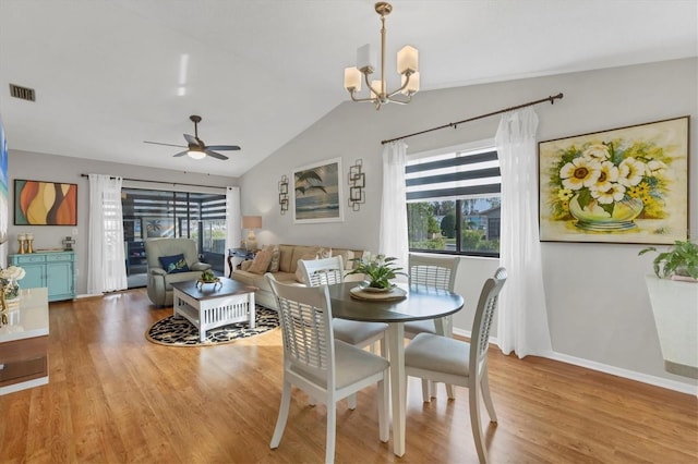 dining room with ceiling fan with notable chandelier, light hardwood / wood-style floors, and lofted ceiling