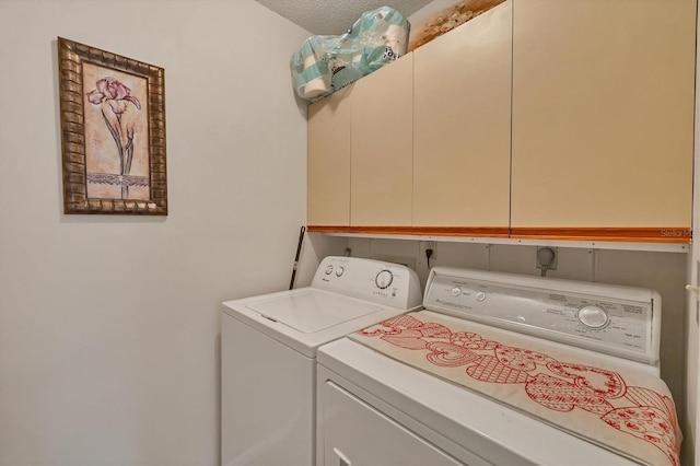 laundry room featuring cabinets, a textured ceiling, and washer and clothes dryer