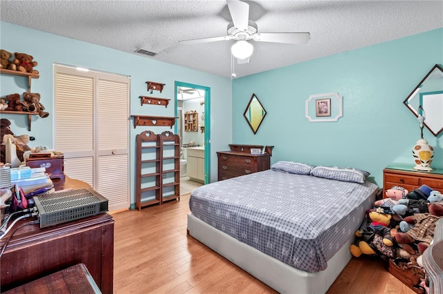 bedroom featuring ensuite bathroom, ceiling fan, light wood-type flooring, a textured ceiling, and a closet