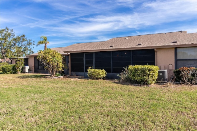 back of property featuring a sunroom, central AC unit, and a lawn