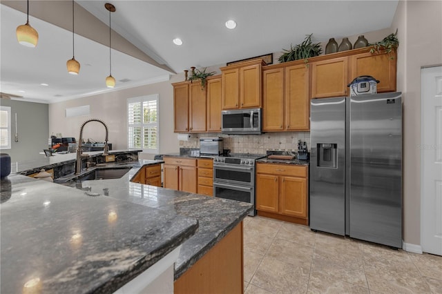 kitchen with sink, dark stone counters, pendant lighting, vaulted ceiling, and appliances with stainless steel finishes