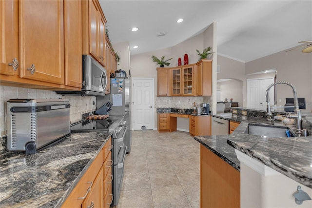 kitchen featuring sink, backsplash, dark stone counters, vaulted ceiling, and appliances with stainless steel finishes