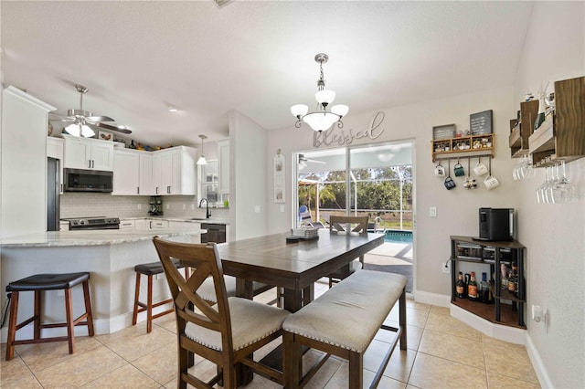 tiled dining space with sink and ceiling fan with notable chandelier