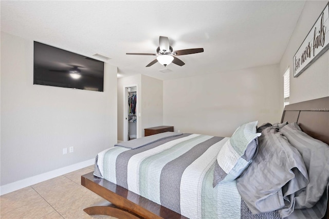 bedroom with ceiling fan, a walk in closet, light tile patterned floors, and a closet