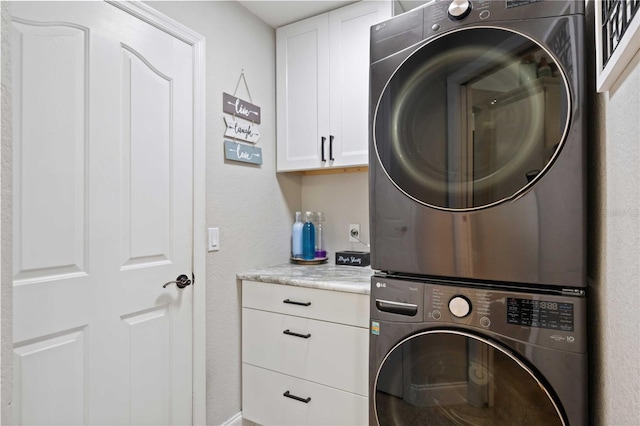 washroom with cabinets and stacked washer and clothes dryer