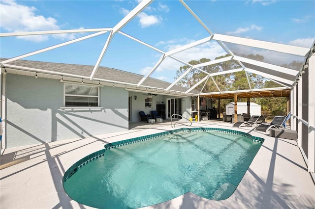 view of swimming pool with a patio, glass enclosure, and ceiling fan