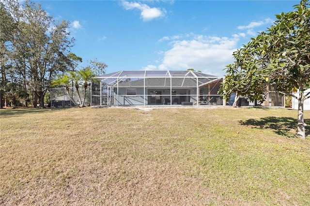 rear view of property with glass enclosure and a yard