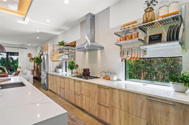 kitchen with light stone countertops, sink, wall chimney range hood, and stainless steel appliances