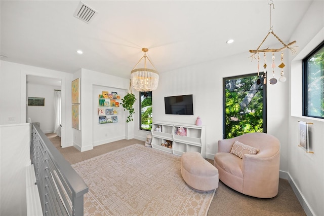 living room featuring a wealth of natural light, light carpet, and a notable chandelier