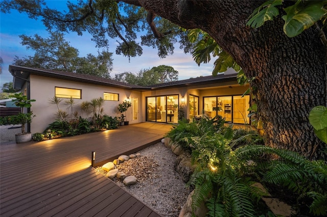 back house at dusk featuring a wooden deck