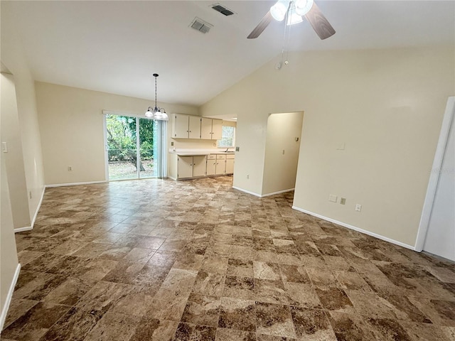 unfurnished living room featuring high vaulted ceiling and ceiling fan with notable chandelier