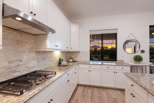 kitchen featuring white cabinetry, light hardwood / wood-style flooring, crown molding, stainless steel gas stovetop, and decorative backsplash