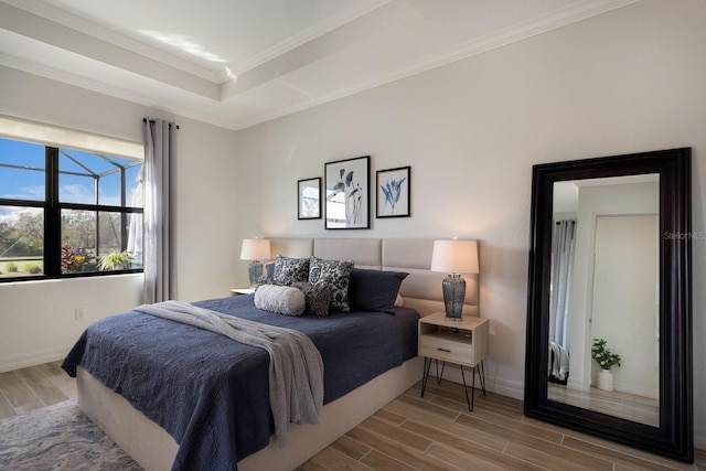 bedroom with hardwood / wood-style floors, a tray ceiling, and ornamental molding