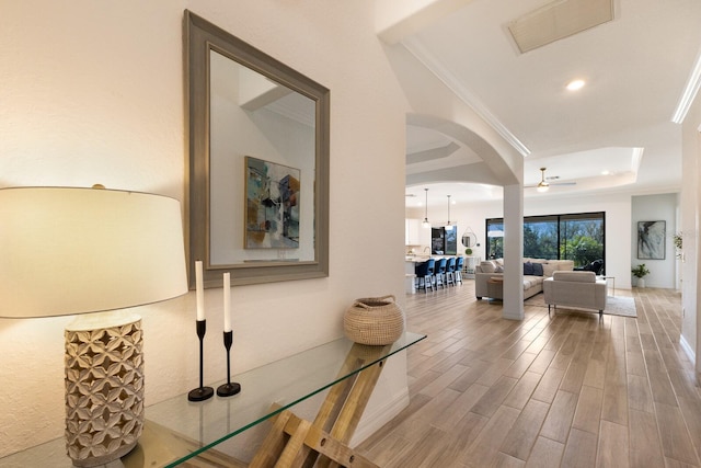 corridor with hardwood / wood-style floors, a tray ceiling, and crown molding