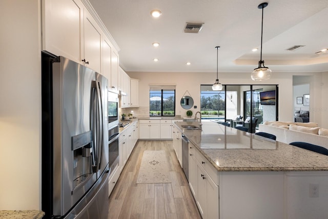 kitchen with white cabinetry, a large island, a tray ceiling, and appliances with stainless steel finishes