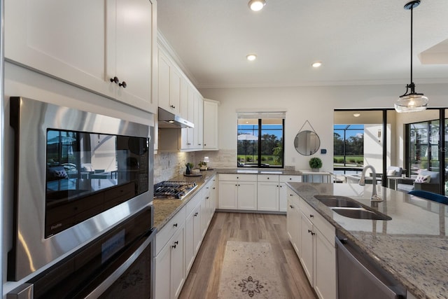 kitchen featuring white cabinets, hanging light fixtures, sink, appliances with stainless steel finishes, and light stone counters