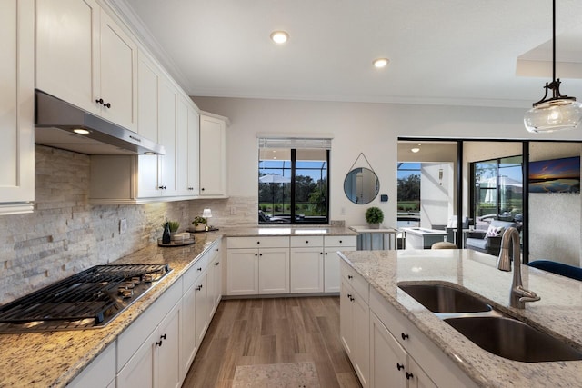 kitchen featuring light stone counters, white cabinetry, stainless steel gas stovetop, and sink