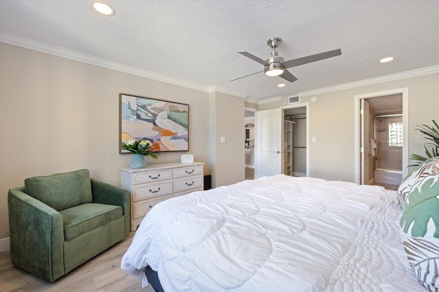 bedroom featuring light wood-type flooring, ensuite bath, a textured ceiling, ceiling fan, and crown molding