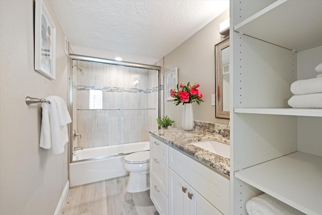 full bathroom featuring hardwood / wood-style floors, a textured ceiling, toilet, vanity, and tiled shower / bath