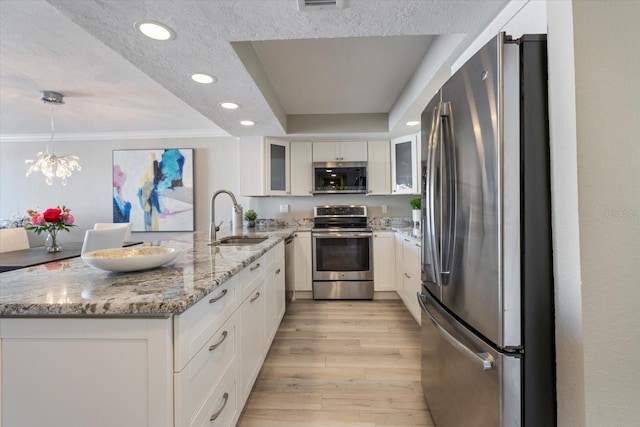 kitchen featuring light stone countertops, appliances with stainless steel finishes, sink, pendant lighting, and white cabinetry