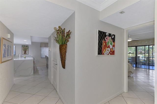 hall with a textured ceiling and light tile patterned flooring