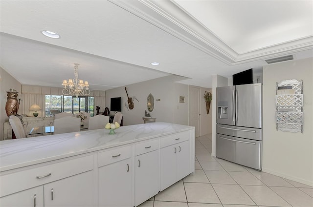 kitchen with an inviting chandelier, stainless steel refrigerator with ice dispenser, ornamental molding, light stone counters, and white cabinetry