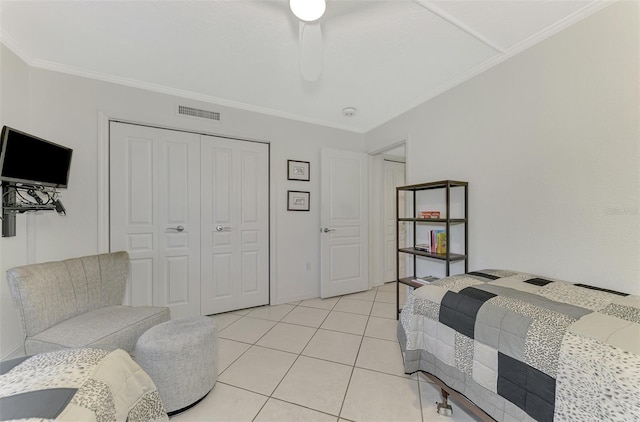 bedroom with ceiling fan, light tile patterned floors, crown molding, and a closet