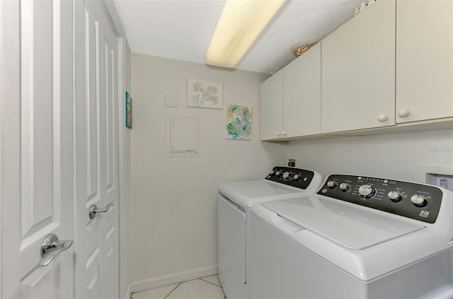 washroom with washing machine and clothes dryer, light tile patterned floors, and cabinets