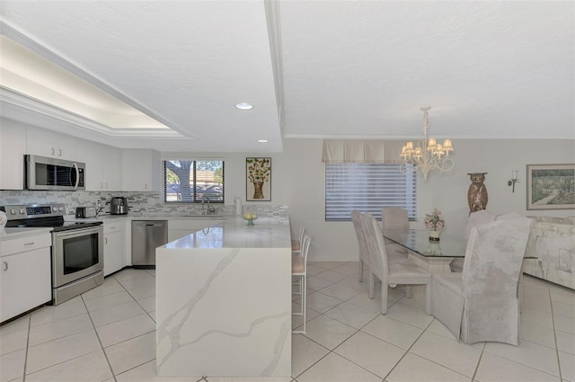 kitchen featuring white cabinets, sink, hanging light fixtures, light tile patterned floors, and stainless steel appliances