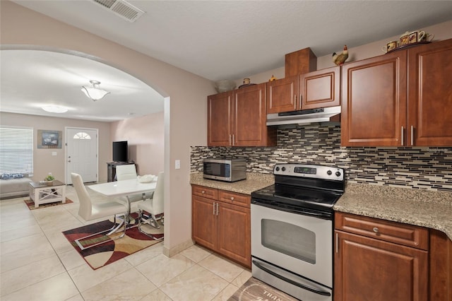 kitchen featuring light stone countertops, light tile patterned floors, stainless steel appliances, and decorative backsplash