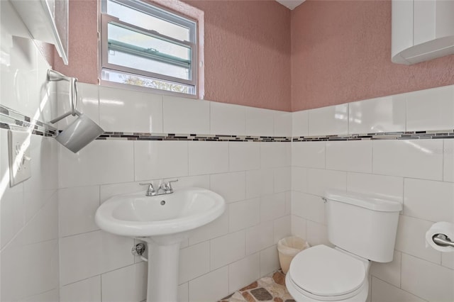 bathroom with toilet and tile walls