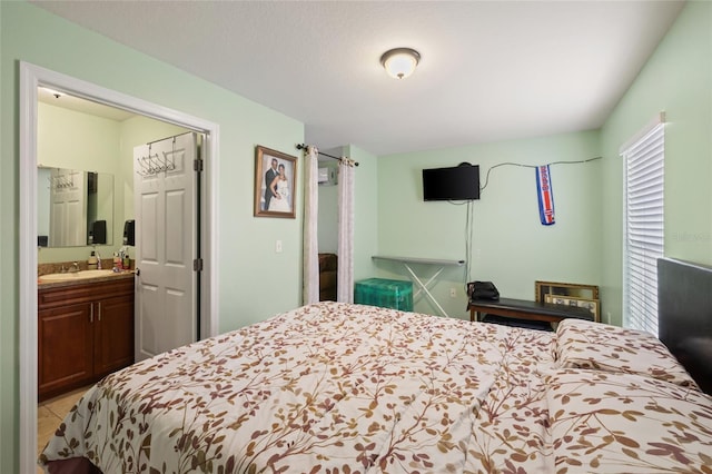 bedroom featuring ensuite bathroom, sink, and light tile patterned floors