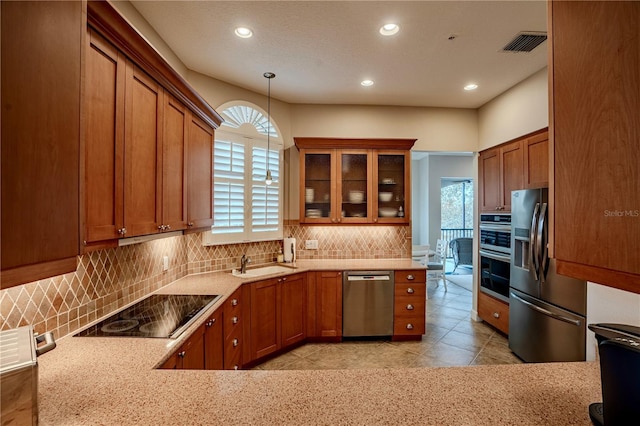 kitchen with pendant lighting, sink, decorative backsplash, stainless steel appliances, and light stone countertops