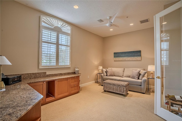 carpeted living room with a textured ceiling, french doors, and ceiling fan