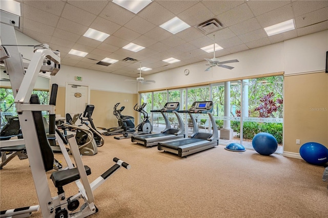 exercise room featuring a high ceiling, a healthy amount of sunlight, a drop ceiling, and ceiling fan