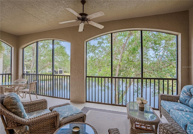 sunroom / solarium with ceiling fan and a water view