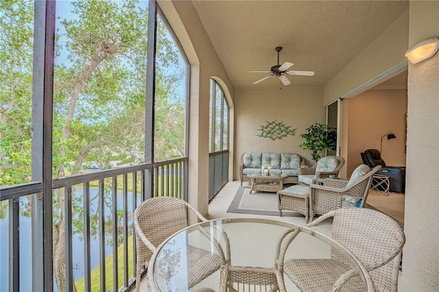 sunroom featuring a wealth of natural light, ceiling fan, and a water view