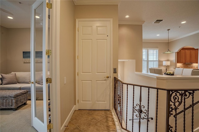 hallway featuring crown molding and light tile patterned floors