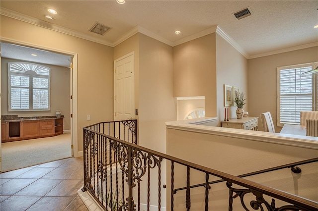 hallway with light tile patterned flooring, crown molding, and a textured ceiling