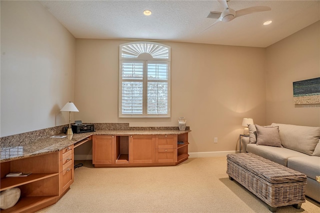 interior space with ceiling fan, built in desk, light carpet, and a textured ceiling