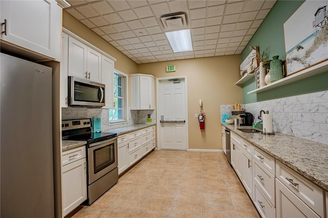 kitchen with stainless steel appliances, sink, white cabinets, and a drop ceiling