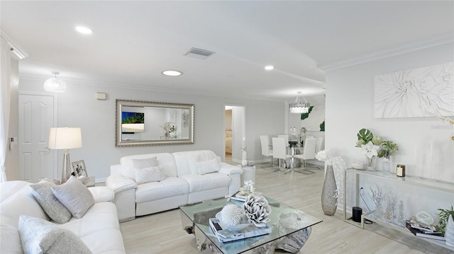 living room with a chandelier, light wood-type flooring, and crown molding