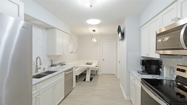 kitchen with white cabinets, decorative backsplash, sink, and stainless steel appliances