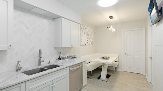 kitchen featuring tasteful backsplash, stainless steel dishwasher, sink, pendant lighting, and white cabinets